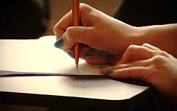 Dłoń trzymająca długopis i pisząca na kartce.